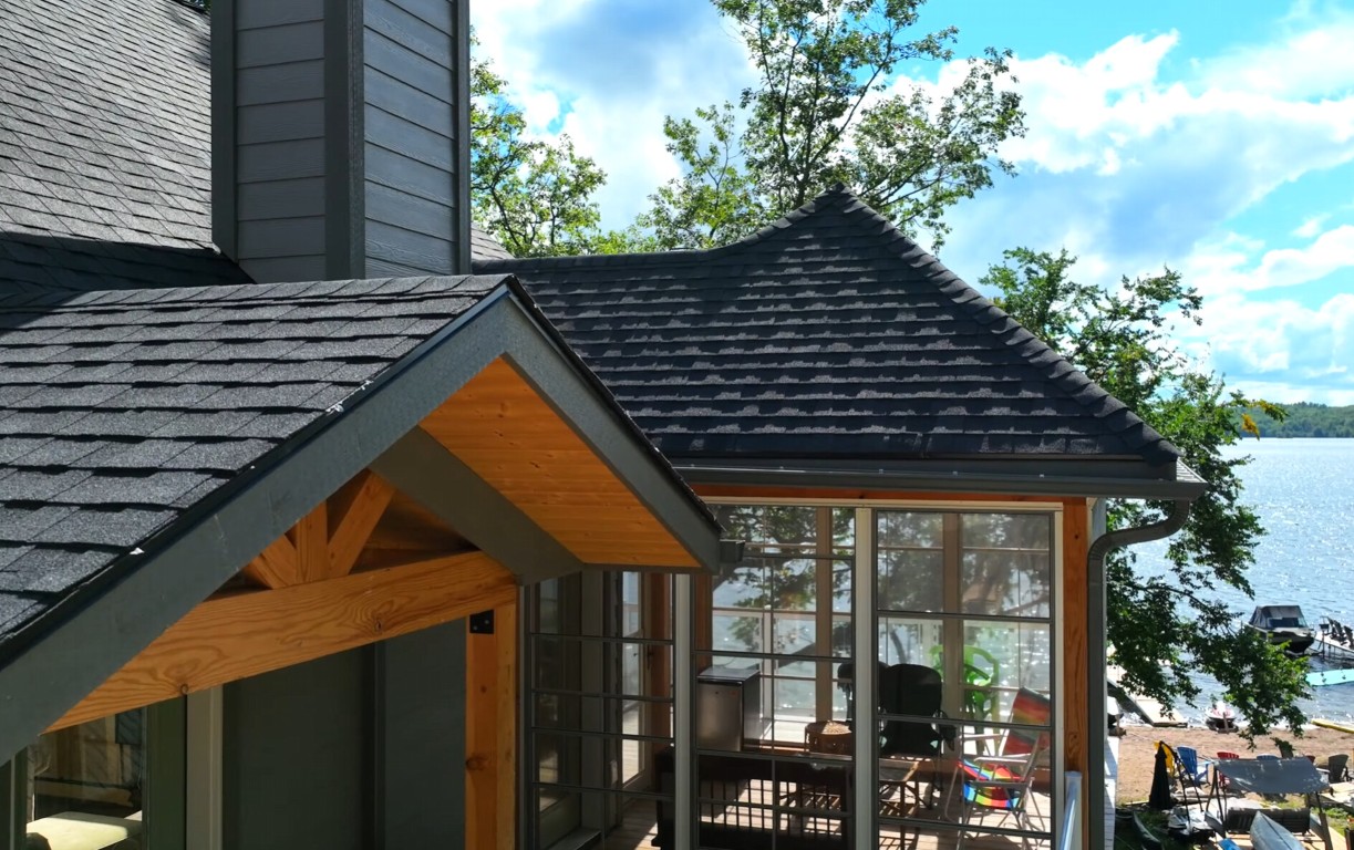 Four-season sunroom with wood beam ceiling and lake views